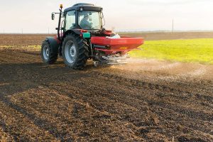 Farm tractor spreading enhanced fertilizers